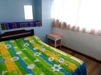 a bedroom with a bed with a green and yellow comforter at Hostal Yumbo Imperial in Quito