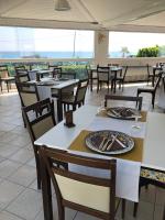 een restaurant met tafels en stoelen en uitzicht op de oceaan bij Hotel Jonio in Noto Marina