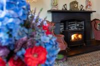 einen Kamin im Wohnzimmer mit Blumen davor in der Unterkunft Taldraeth - Old Vicarage Guest House in Penrhyndeudreath