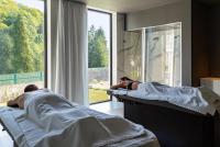 two people laying in beds in a room with a window at 6717 Nature Hôtel &amp; Spa Le Clos des Délices in Ottrott