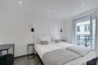a white bedroom with a large bed and a window at Le Bellevue in Paris
