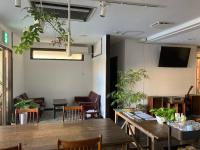 Un comedor con mesas de madera y plantas. en J-Hoppers Beppu Guesthouse ジェイホッパーズ別府ゲストハウス, en Beppu