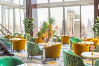 a restaurant with yellow chairs and tables and windows at Shangri-La The Shard, London in London