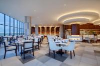 a restaurant with white tables and chairs and windows at Wyndham Opi Hotel Palembang in Palembang