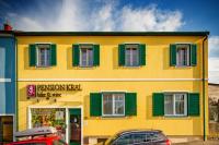 a yellow building with green shutters and cars parked in front at Pension Kral in Rust