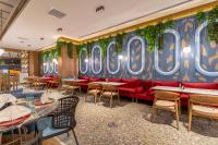 Un restaurante con un sofá rojo y mesas y sillas. en Mercure Trabzon Hotel, en Trabzon