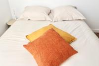 a white bed with white pillows and a orange pillow at Napoléon Gare 5 STUDIO 1er Etage ByLocly in Pontivy