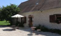 a building with a table and chairs and an umbrella at Chambres d&#39;Hôtes L’Échappée Belle in Saint-Brisson-sur-Loire