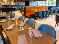 Un restaurante con mesas de madera y sillas azules. en Logis Clermotel - Hôtel & Restaurant, en Agnetz