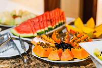 a plate of fruit on a table with plates of food at Búzios Centro Hotel in Búzios