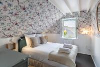 a bedroom with a bed with a flowery wallpaper at Le Phare Bleu - near center &amp; beach - 2 to 4 P in Honfleur