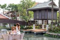 two women sitting at a table in front of a house at Grand Mercure Khao Lak Bangsak in Khao Lak