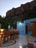 Dos personas sentadas en una mesa con una montaña al fondo. en MH Guest House, en Jodhpur