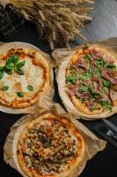 three pizzas sitting on paper on a table at Žilvinas Hotel in Palanga