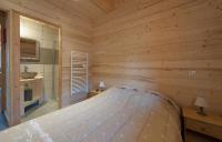 a bedroom with a bed in a wooden room at Odalys Chalet D&#39;Alice in Les Menuires