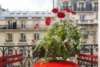 a planter with red flowers on top of a balcony at New Orient Hotel in Paris