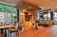 um restaurante com mesas e cadeiras e grandes janelas em voco The Hague by IHG em Haia