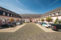 Un gran edificio con coches aparcados en un estacionamiento. en Schlosshotel Weilburg, en Weilburg