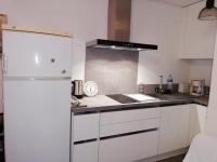 a kitchen with white cabinets and a refrigerator at Appartement avec terrasse in Saint-Cyprien-Plage