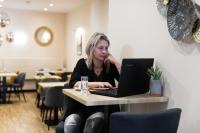 a woman sitting at a table with a laptop computer at Hôtel Le Florin in Rennes
