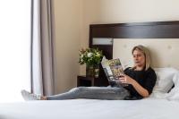 a woman sitting on a bed reading a book at Hôtel Le Florin in Rennes