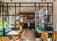 Un restaurante con mesas y sillas y un bar. en KYRIAD LYON OUEST Limonest, en Limonest