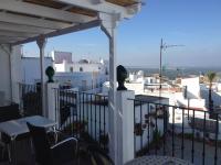 a balcony with tables and chairs and a view of a city at Apartamentos Casa la Costanilla in Vejer de la Frontera