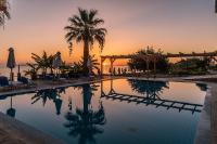 Una piscina con una puesta de sol al fondo en Belussi Beach Hotel &amp; Suites, en Kypseli