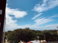 a blue sky with clouds and trees on a street at The Deer Head Inn in Kenting