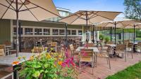 un patio con mesas, sillas y sombrillas en Best Western Plus Windjammer Inn & Conference Center, en Burlington