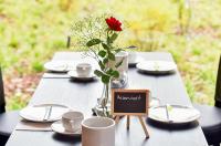 Una mesa con un jarrón con una rosa roja encima. en PRIMA Inn HOTEL & HOF NEURUPPIN - digitales & rezeptionsloses Motel, en Neuruppin