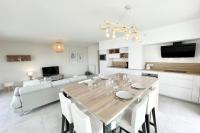 a kitchen and living room with a wooden table and chairs at Spacieux appartement neuf de standing Hyper Cosy in Larmor-Plage