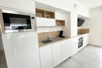 a white kitchen with a sink and a microwave at Spacieux appartement neuf de standing Hyper Cosy in Larmor-Plage