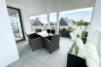 a patio with a table and chairs on a balcony at Spacieux appartement neuf de standing Hyper Cosy in Larmor-Plage