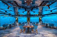a restaurant with blue walls and tables and chairs at Anantara Kihavah Maldives Villas in Baa Atoll