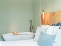 a bath tub sitting next to a bed with pillows at Nature and Haven of Peace Apartment in Paris