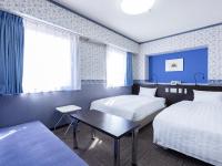 una habitación de hotel con dos camas y una mesa en Hotel Wing International Shimonoseki, en Shimonoseki