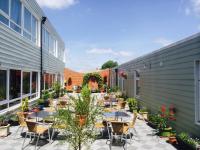 Un patio al aire libre con mesas, sillas y plantas. en Star Anglia Hotel, en Colchester
