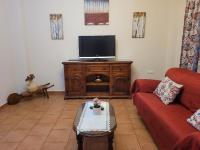 a living room with a red couch and a flat screen tv at El Corral de Dolores in El Bosque