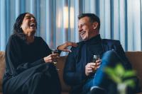 Un hombre y una mujer sentados en un sofá sosteniendo copas de vino. en Medlefors Hotell & Konferens, en Skellefteå