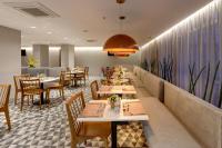 Un restaurante con mesas y sillas de madera y una pared larga. en Comfort Hotel Guarulhos Aeroporto, en Guarulhos