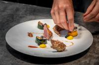 una persona recogiendo comida en un plato blanco en Auberge de Clochemerle - Spa & Restaurant gastronomique étoilé, en Vaux-en-Beaujolais