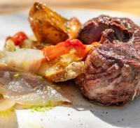 Un trozo de carne y verduras en un plato. en Hotel Esteba, en Caldes de Malavella