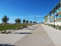 a long sidewalk next to a building with trees at Apartment L&#39;Oustalet-3 by Interhome in Mimizan-Plage