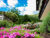 a garden with pink flowers and a log at Studio Dirndl und Bua by Interhome in Donnersbachwald