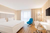 a hotel room with a large bed and a blue chair at NH Mannheim in Mannheim