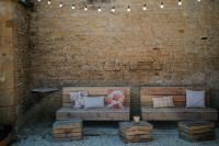 a wooden bench sitting against a brick wall with pillows at Le Domaine de l&#39;Hostellerie in Le Fresne-Camilly