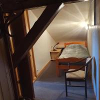 a bedroom with a bed and a chair in a attic at La Clé des Champs in Les Fourgs