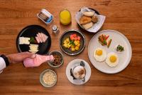 Uma mesa com pratos de comida de café da manhã e uma pessoa servindo comida. em ibis styles Lima San Isidro em Lima