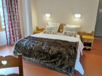 a bedroom with a large bed with a blanket on it at Auberge du Freney in Le Freney-dʼOisans